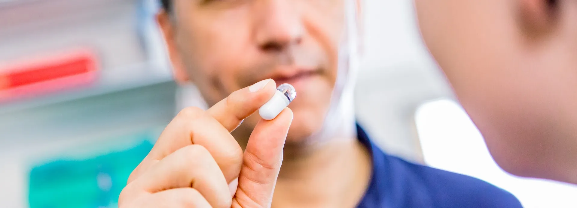 Patient hält eine Kapsel für die Kapselendoskopie vor den Mund